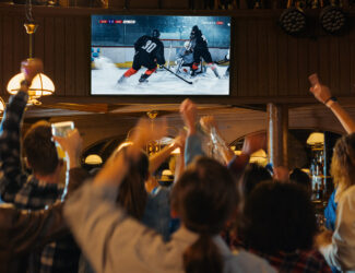 Fans in a pub watching hockey and cheering together